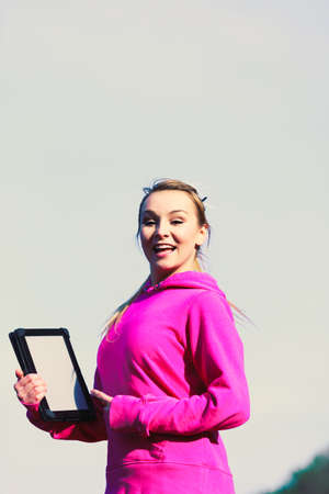 Young pretty girl in park pointing at tablet showing screen. Having fun with technology.の写真素材