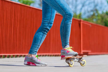Summer sport and active lifestyle. Cool teenage girl human legs skater riding skateboard on the...
