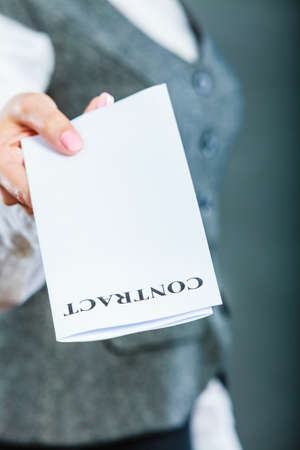 Business documents legal concept - closeup serious businesswoman holding contract in handの写真素材