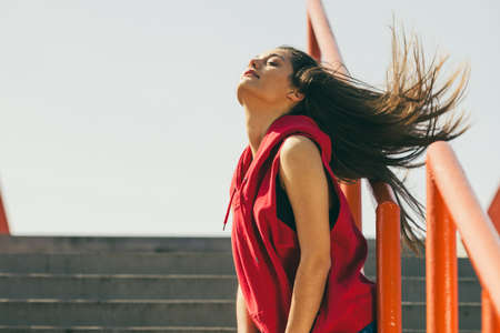 Young long haired girl on city stairs feeling wind in hair. Lifestyle funky in summer.