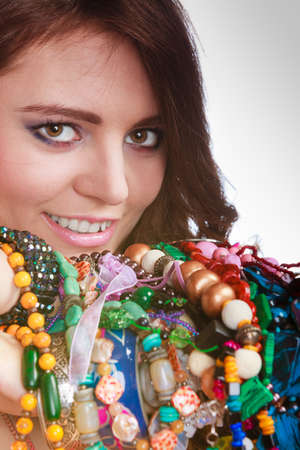 Pretty young woman wearing bracelets holding many plentiful of precious jewelry necklaces beads. Portrait of gorgeous fashion girl in studio on gray.の写真素材