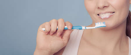 Young woman brushing cleaning teeth. Girl with toothbrush. Oral hygiene.の写真素材