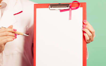Doctor with diagnosis. Part body of female specialist holding red folder with disease files. Pink breast cancer awareness ribbon.の写真素材