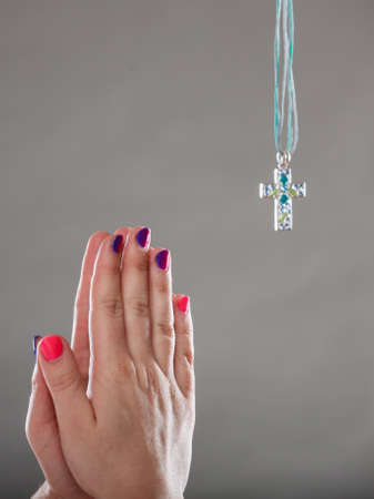 Human hands praying to god jesus christ with cross necklace pendant. Strong christian religion faith. Christianity.の写真素材