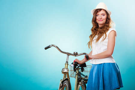 Happy joyful young woman with bike bicycle. Fashionable girl in hat, white shirt and skirt. Summer fashion and recreation. Studio shot.の写真素材
