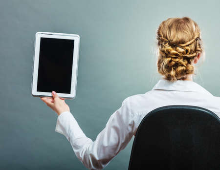 Modern technologies concept. Business woman sitting on chair with computer tablet showing blank copy...