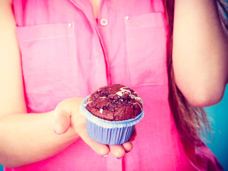 sweet food and people concept. summer fashionable woman wearing pink shirt holds cake cupcake in hand closeupの写真素材