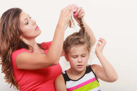 Mother combing daughter, care about hairstyle. Girl is unhappy mom pulling her hair. Important role in child life.の写真素材