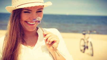 Holidays and vacation. Lovely cute woman tourist holding little flower on sunny beach. Young girl...