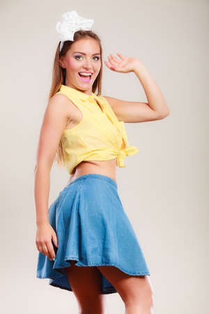 Alluring seductive pretty pin up girl wearing hairband bow and skirt. Attractive gorgeous young retro woman dancing on table.の写真素材