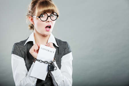Business concept. Serious businesswoman with chained hands holding contractの写真素材