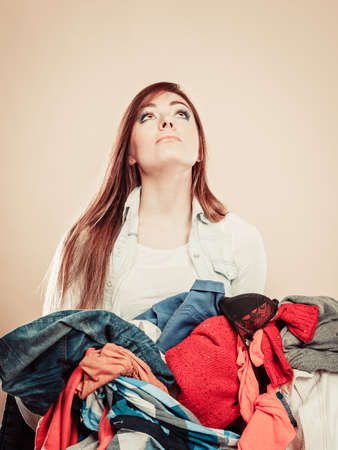 Daily routine in household laundry wash and ironing. Young girl hold pile of colorful clothes.の写真素材