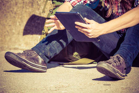 Man tourist backpacker relaxing outdoor sitting by grunge wall using tablet. Internet, tourism active lifestyle. Young hipster guy trampingの写真素材