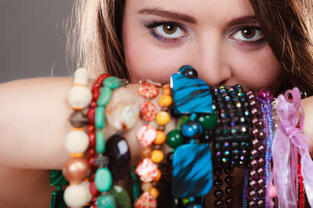 Pretty young woman wearing bracelets holding many plentiful of precious jewelry necklaces beads....