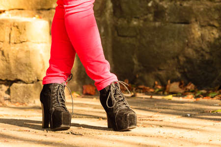 Female footwear. Part body woman wearing black elegant shoes high heels. Stylish girl in red trousers outdoor in park.の写真素材