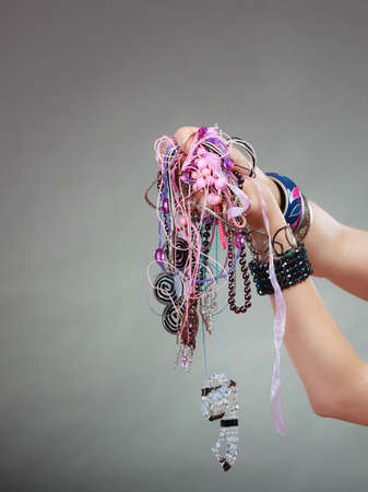 Closeup of woman hand palm holding many plentiful of precious jewelry necklaces beads. Fashion girl...