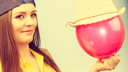 Joy and fun. Beauty smiling teenage girl with red pink balloon. Young charming trendy woman in fashion clothes against blue background.の写真素材