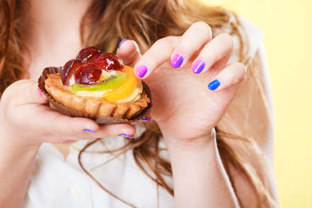 Bakery sweet food and people concept. Fruit cake cupcake on woman hand closeupの写真素材