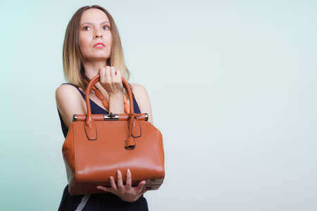 Elegant fashionable woman with leather handbag. Stylish girl on green holding brown bag. Women fashion vogue. Studio.の写真素材