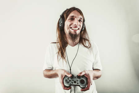 Playing games. Young smiling cheerful man play on console. Guy with pad joystick.の写真素材