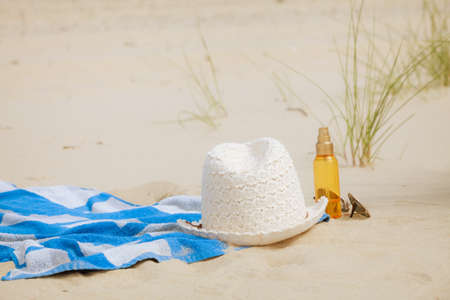 Beach set summer hat sunglasses and skin lotion lying on the sand. Vacation resting and relaxの写真素材
