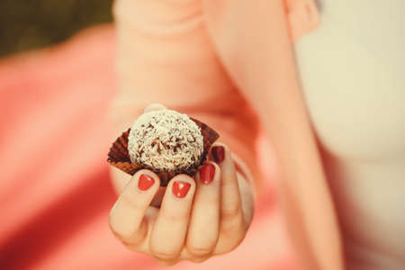 Food and sweets. Appetite and tasty meal dessert. Part body woman with little cookie cupcake. Hand holding small cake.の写真素材