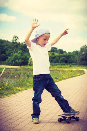 Sporty child balancing on skateboard outdoor. Active boy skateboarding on pavement sidewalk. Kid practicing outside.の写真素材