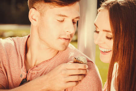 Love and dating. Young handsome man flirting with attractive woman by cupcake cookie. Happy cute lovers on date outdoor.の写真素材