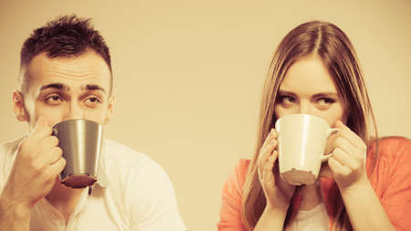 Happiness and healthy relationship concept. Attractive couple drinking tea or coffee together, man and woman holding mugs with hot beverageの写真素材