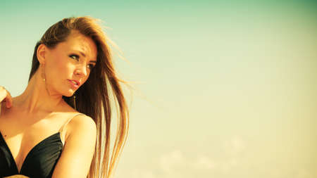 Holidays, summertime travel and freedom concept. Portrait of lovely girl beauty long hair outdoor. Young pretty tanned woman in summer clothing on sky backgroundの写真素材
