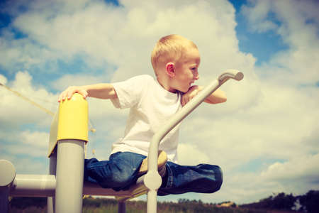 Child having fun in playground. Boy hanging on leisure equipment. Kid climbing and playing. Active and happy childhood.の写真素材