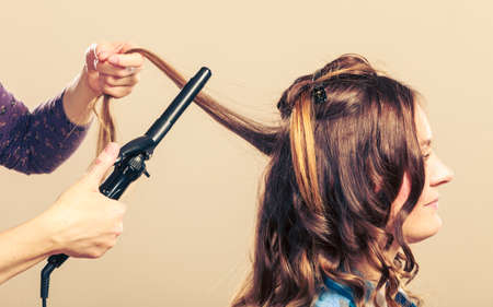 Stylist curling hair for young woman. Girl care about her hairstyleの写真素材
