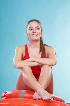 Happy lifeguard sitting on rescue tube buoy and ring lifebuoy. Joyful woman girl having fun. Accident prevention and rescue.の写真素材