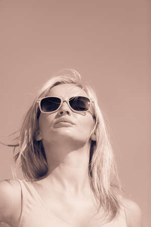 Young blonde pretty girl on beach. Woman wearing sunglasses have active time in summer. Summertime concept.の写真素材
