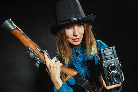 Photography and retro style. Young vintage attractive girl holds old aged camera. Steampunk...
