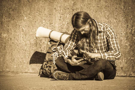 Man tourist backpacker relaxing outdoor sitting by grunge wall using tablet. Internet, tourism...