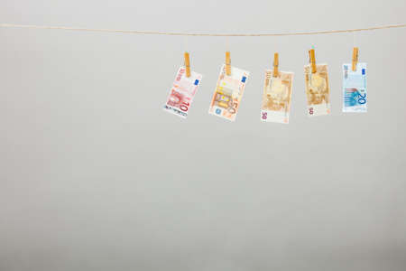 Banknotes cash money hang on laundry line on gray grey background.の写真素材
