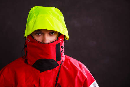 Male outdoorsman with covered face. Young man wearing waterproof oilskin. Adventure outdoor action danger concept.の写真素材