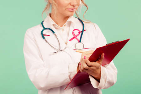 Diagnosis of breast cancer. Blonde middle aged female holding red folder with files of desease...