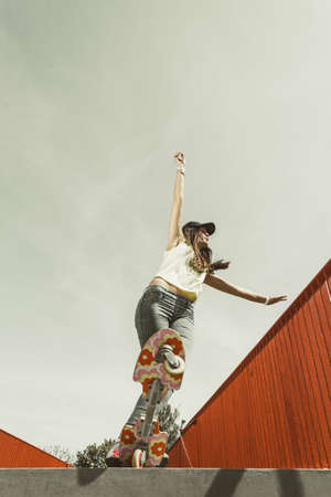 Summer sport and active lifestyle. Cool teenage girl in full length skater riding skateboard on the...