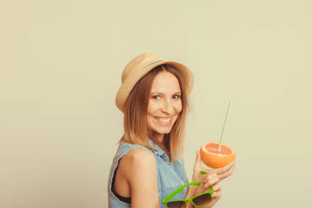Happy glad woman tourist in straw hat holding sunglasses and grapefruit citrus fruit. Healthy diet food. Summer vacation holidays concept.の写真素材
