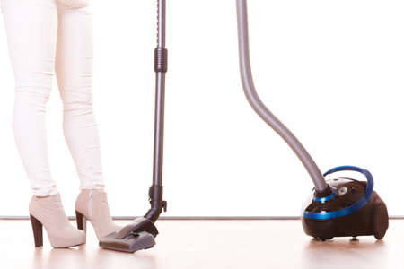 Woman vacuuming the house. Female legs with vacuum cleaner. Housework