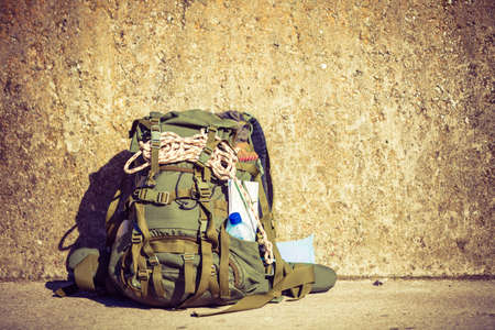Hiking backpack camping and mountain exploring tourist equipment outdoor on grunge wall. Adventure,...