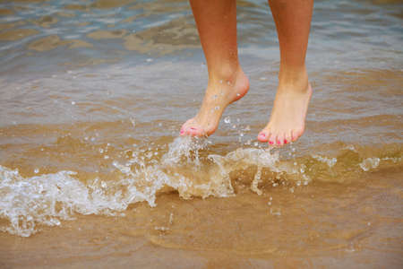 Happiness and craziness. Female legs feet in air jump on beach over water. Fun and freedom.の写真素材