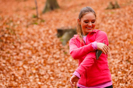 Rest and relax. Young attractive sporty girl with mobile phone smartphone on her arm with headphones listening music.の写真素材
