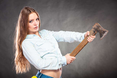 Sexy seductive woman holding axe chopper. Strong girl feminist working in man profession. Independent female. Studio shot.の写真素材