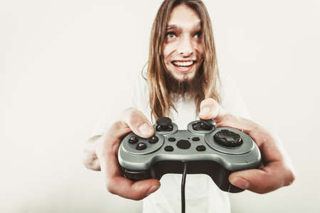 Playing games. Young smiling cheerful man play on console  . Guy with pad joystick.の写真素材