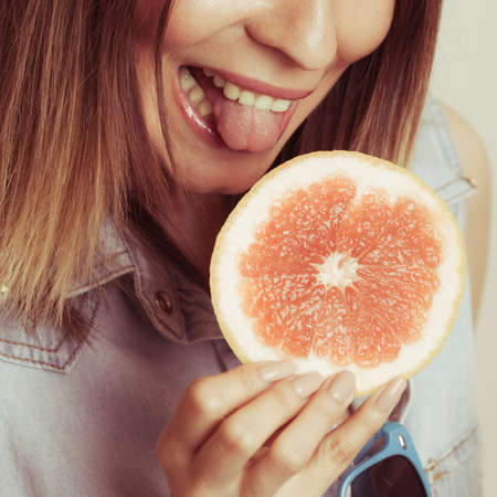Happy glad woman eating grapefruit fruit. Healthy diet food. Weight loss. Summer vacation holidays.の写真素材