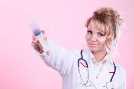 Injection concept. Female doctor with close up big syringe and stethoscope. Medical help and prevention for disease.の写真素材
