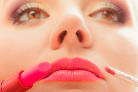Close up of woman applying lipstick with brush on lips. Girl beautifying herself. Beauty and make up concept.の写真素材
